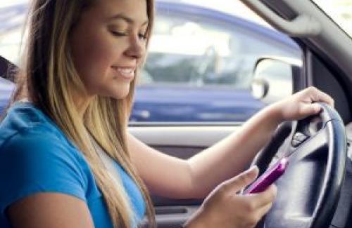 Teenager at the wheel looking at her phone