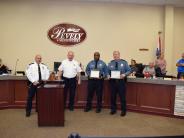 Group of four standing at podium holding certificates