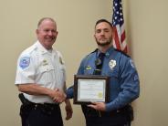 Younger officer with beard holding certificate and shaking another officers hand