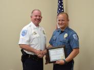 Younger blonde officer holding certificate and shaking another officers hand