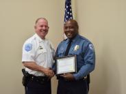 Smiling Officer holding certificate while shaking another officers hand